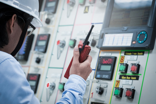 Industrial engineer working operated control panel with talking on the walkie-talkie