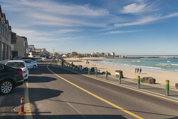 Beautiful scenery of coastal road alongside Woljeong Beach Jeju, South Korea with road-side shoplots. Awesome blue sky and ocean background. Selective focusing.