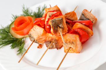 Fish salmon barbecue kebab on skewer on a white plate