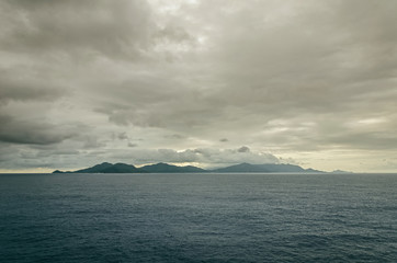 Black island at the sea under the clouds