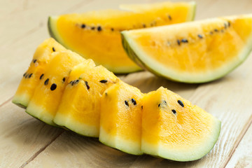 Yellow watermelon sliced on wooden background