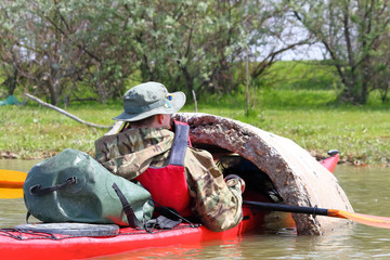 Man in red kayak in red life jacket kayaking in wild Danube river on biosphere reserve in spring