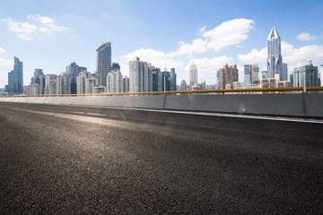 empty asphalt road with cityscape of modern city in blue sky