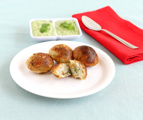 Two broken pieces of paddu, a south Indian vegetarian food usually made from a batter of lentils and rice.