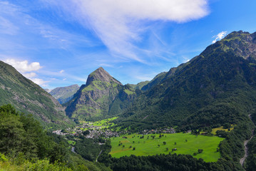 Obraz na płótnie Canvas Panoramica delle montagne con abeti e prati verdi, con cielo blu e nuvole bianche