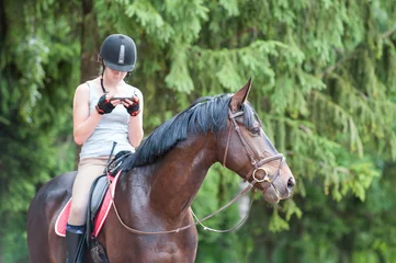 Foto op Canvas Chestnut horse with teenage girl with smartphone sitting on it © AnnaElizabeth