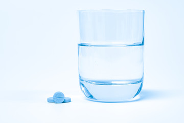 Pills and medication and a glass with water on a white background