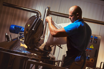 Brewer in brewhouse pouring out the malt to the tank