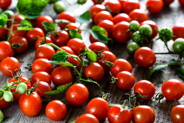 Basket of tomatoes called cherry tomato on wooden background, fresh produce on the kitchen table, top view