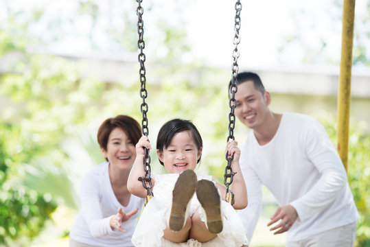 Young Happy Asian Family Spending Time Together At The Playground.