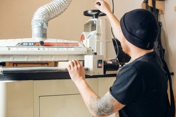 male carpenter builder working overall equals wooden bar with a milling machine