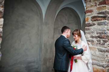 Fabulous wedding couple walking and posing next to the old building.