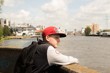 boy in a red cap stands near the river