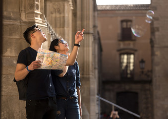 Young tourist couple walking in Barcelona city pointing with a map in hand