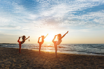 A group of women doing yoga at sunrise near the sea
