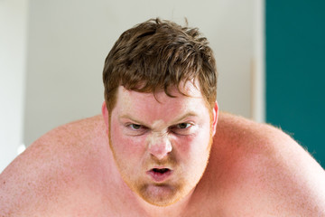 Obraz premium Rothaariger junger dicker Mann schreit wütend und zerreißt sein Shirt