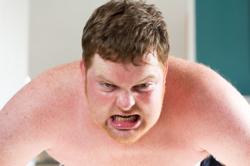 Obraz premium Rothaariger junger dicker Mann schreit wütend und zerreißt sein Shirt