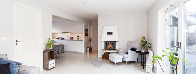 panorama of a cozy living room with lit fireplace, glass doors, 