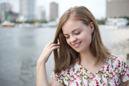 Portrait of young smiling caucasian woman, with embankment area at background  