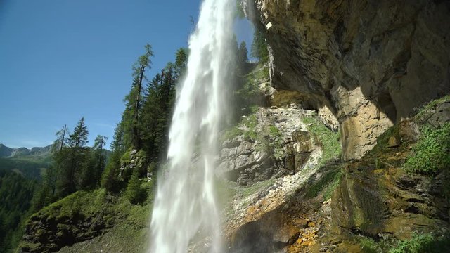 4k nature loop able 5 sec video waterfall over rocks in forest with blue sky, sunshine and audio
