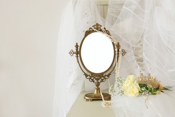 Old vintage oval mirror and beautiful white wedding dress and veil on chair