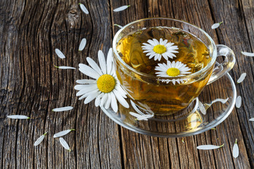 Obraz na płótnie Canvas Cup of medicinal chamomile tea on a wooden