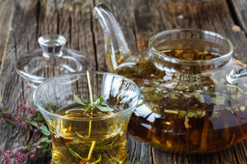 Middle East Black tea with thyme, ethnic glass and glass teapot, vintage wood background