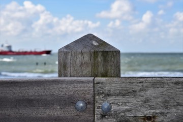 Wooden fence at the beach with passing ship