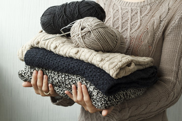 Picture of cozy knitted woolen sweaters in woman's hands
