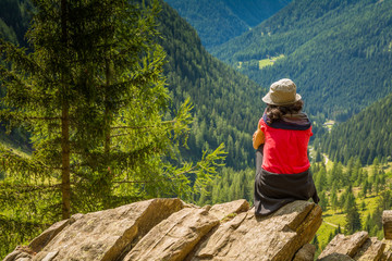 traveler young lady standing on top of the mountain and enjoyng valley view. Rabbi valley, Trentino Alto Adige, Italy