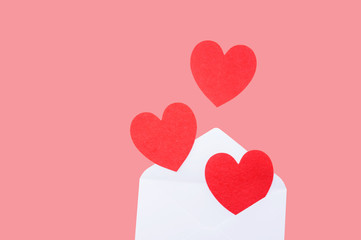 Red heart in a white envelope on a pink background.