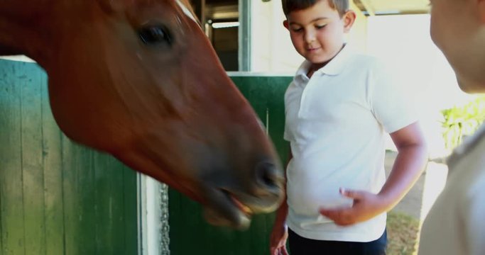 Kids stroking horse in stable 