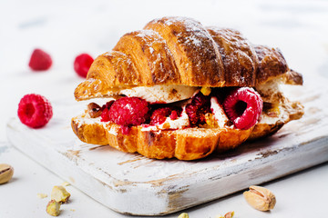 French croissants with cream cheese and raspberry, cinnamon and almond nuts. Copy space