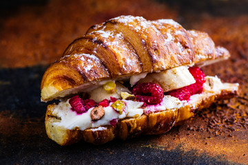 French croissants with cream cheese and raspberry, cinnamon and almond nuts. Copy space