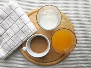Top view of  drink for breakfast or meal included with  tasty hot coffee,orange juice,milk in cup put on wood plate and napkin.
