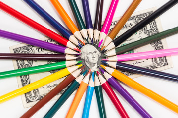 Color pencils lie all around the portrait on a one-dollar bill.