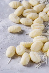 Raw uncooked potato gnocchi with flour and grated parmesan cheese over gray concrete background. Close up. Home cooking.