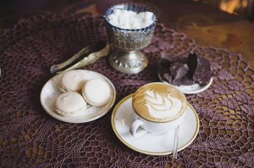 Coffee latte on the wooden retro table. Brekfast with chocolate and macaroons