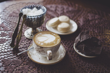 Cappuccino breakfast with chocolate and macaroons. Retro cafe. Coffee latte on the knitted tablecloth