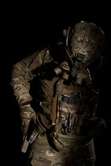Fototapeta na wymiar Soldier in military uniform reaching for pistol on background of dark wall 24