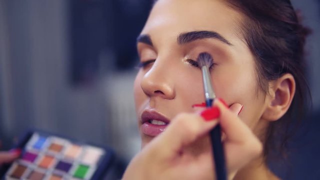 Professional make-up artist applying eyeshadow to model eye using special brush. Beauty, makeup and fashion concept. Slowmotion shot