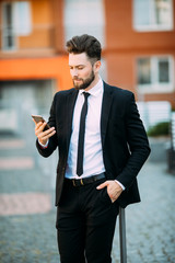 Young urban professional man using smart phone. Businessman holding mobile smartphone using app texting sms message