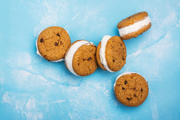 Homemade vanilla ice cream sandwiches with chocolate drops cookies on blue background. Copy space