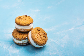 Homemade vanilla ice cream sandwiches with chocolate drops cookies on blue background. Copy space