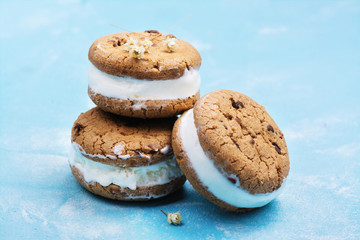 Homemade vanilla ice cream sandwiches with chocolate drops cookies on blue background. Copy space