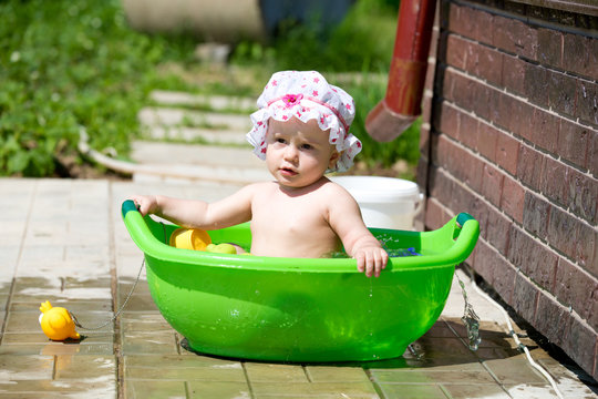 Baby girl playing in the bath outdoors