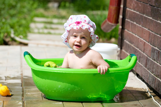 Baby girl playing in the bath outdoors