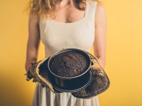 Young woman holding a burnt cake