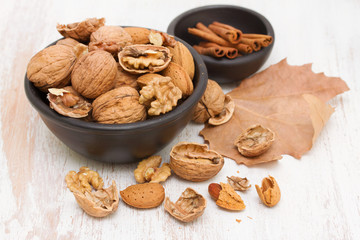 walnuts and almond on black bowl on wooden background