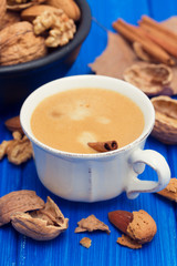 a cup of coffee and nuts on wooden background